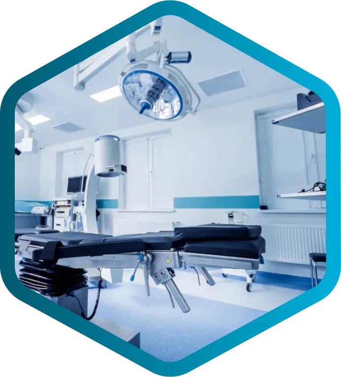A modern, empty operating room with surgical lights, equipment, and an adjustable operating table in a clean, well-lit medical facility.